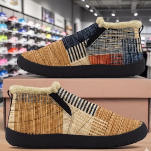 May include: A pair of slip-on ankle boots featuring a quilted upper with a patchwork pattern of tan, brown, and navy blue textured lines. The boots have a thick black rubber sole and a cream-colored faux fur lining around the top collar opening.