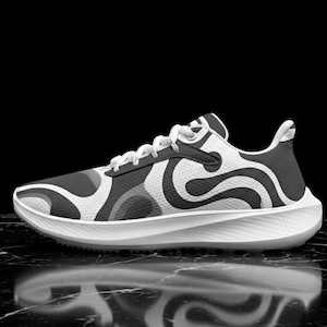 May include: A low-top sneaker featuring a white base with a dark gray abstract swirling pattern across the upper. The shoe includes white laces, a structured dark gray eyelet panel, and a thick, textured white foam sole with a rounded heel design.