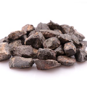 Pode incluir: Um conjunto de pequenas pedras de formato irregular, de cor castanho-escura e preta, com uma textura rugosa e porosa. As pedras variam em tamanho e têm bordas irregulares, criando uma pilha densa com cavidades visíveis nas superfícies.