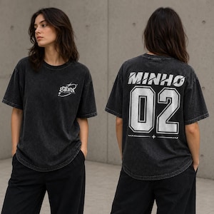 May include: A charcoal grey acid-wash t-shirt featuring a small white 8TURN logo on the front left chest. The back of the shirt displays the name MINHO in large white letters above the number 02, both styled with a metallic silver effect.