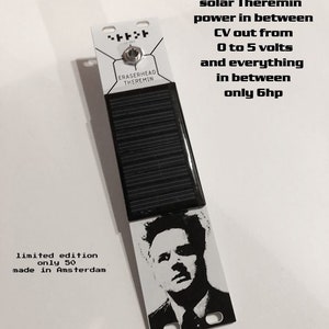 Puede incluir: Un instrumento musical electrónico blanco y negro llamado "Eraserhead Theremin" con un panel solar en la parte superior. El instrumento funciona con energía solar y emite una señal CV de 0 a 5 voltios. El texto "edición limitada solo 50 fabricados en Ámsterdam" está impreso en la esquina inferior izquierda de la imagen.