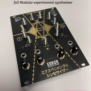 May include: A black and gold modular synthesizer with the text "cloudbusting gold" and "full Modular experimental synthesiser" above it. The synthesizer has a variety of knobs, buttons, and jacks. The text "ERROR instruments" and "エクスペリメンタル シンセサイザー" is also visible on the synthesizer. The text "VOODOO PATCHING" is visible below the synthesizer.