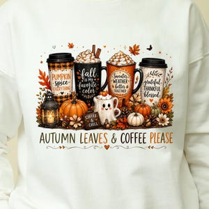 May include: A cream-colored crewneck sweatshirt featuring a graphic print of four coffee cups, a lantern, pumpkins, and autumn leaves. The text reads "PUMPKIN SPICE EVERYTHING," "fall IS MY favorite color," "SWEATER WEATHER better TOGETHER," "grateful THANKFUL blessed," "COFFEE & CHILL," and "AUTUMN LEAVES & COFFEE PLEASE."
