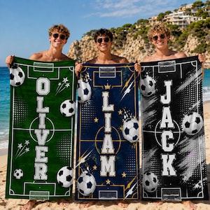 Può includere: Tre teli mare rettangolari con grafiche di campi da calcio e nomi personalizzati. Il telo verde mostra il nome OLIVER, quello blu LIAM e quello nero JACK. Ogni telo include illustrazioni di palloni da calcio.