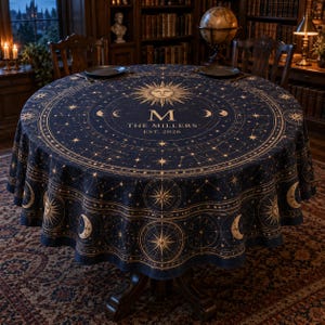 May include: A round navy blue tablecloth featuring a gold celestial print with stars, moons, and sun motifs. The center displays a large sun, the letter M, and the text THE MILLERS EST. 2026. The design includes intricate compass-like patterns.