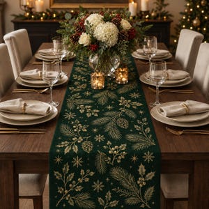 May include: A dark green table runner featuring a gold-toned print of pine branches, pinecones, holly leaves, berries, and snowflakes. The runner is centered on a wooden dining table set with white plates, linen napkins, and clear glassware.