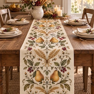 May include: A cream-coloured fabric table runner featuring a repeating botanical print of golden pears, wheat stalks, green leaves, and red berries. The runner is centred on a wooden dining table set with white plates, napkins, and candles.