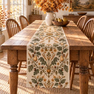 May include: A rectangular table runner featuring a repeating botanical pattern on a light beige fabric. The design includes green oak leaves, golden yellow flowers, brown acorns, and light brown pears arranged in a symmetrical, ornate layout.