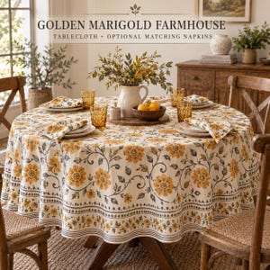 May include: A round tablecloth featuring a cream background with a repeating pattern of golden yellow marigold flowers and grey leafy vines. The border includes a decorative geometric band. The text reads GOLDEN MARIGOLD FARMHOUSE.