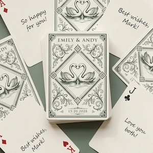 May include: A deck of custom playing cards featuring a swan illustration and the text Emily & Andy 15.20.2028. Individual cards display messages including So happy for you!, Best wishes, Mark!, and Love you both! alongside traditional card suits.
