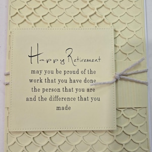 Peut inclure: Une carte de retraite cr&egrave;me avec les mots "Happy Retirement" en &eacute;criture &eacute;l&eacute;gante. La carte pr&eacute;sente un fond textur&eacute; et &agrave; motifs et un petit carr&eacute; cousu avec un message sinc&egrave;re. Un n&oelig;ud en ficelle ajoute une touche d&eacute;corative.