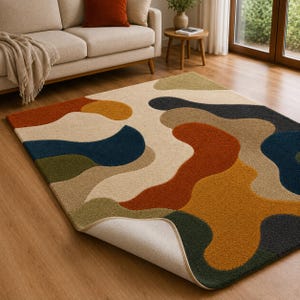 May include: A rectangular area rug featuring an abstract pattern of organic, flowing shapes in shades of burnt orange, deep blue, olive green, charcoal gray, and cream. The rug has a textured pile surface and one corner is folded over to reveal the backing.