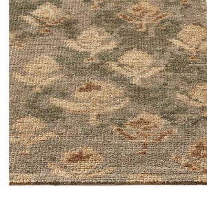 Peut inclure: Un tapis tissé présentant un motif floral répétitif dans des tons vert sauge et crème. Le textile possède un poil épais et texturé avec des boucles visibles, créant une surface dense avec des variations de couleurs douces et terreuses.