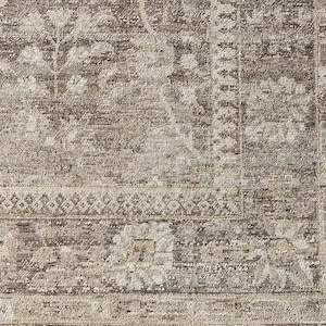 May include: A woven area rug featuring a distressed, faded pattern in shades of taupe, beige, and dark brown. The design includes intricate floral motifs, scrolling vines, and a geometric border, all rendered with a textured, low-pile appearance.