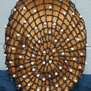 May include: A black hair net with white pearl beads. The net is made of a fine mesh material and is designed to hold hair in place.