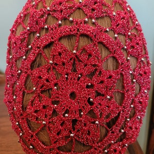 May include: Red crochet hair bun cover with silver beads.