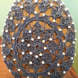 May include: A gray crochet hairnet with a circular design and white pearl beads.