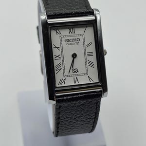 Reloj de pulsera vintage Seiko Slim Tank de cuarzo con esfera blanca con números romanos y caja rectangular plateada de 27 mm para hombre.