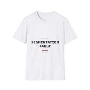 Può includere: Una t-shirt bianca a maniche corte con il testo CRASH REPORT in lettere piccole, seguito dal testo nero in grassetto SEGMENTATION FAULT, una sottile linea orizzontale rossa e il testo core dumped in piccole lettere rosse centrato sul petto.