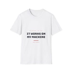 Könnte beinhalten: Ein weißes Kurzarm-T-Shirt mit dem schwarzen Text IT WORKS ON MY MACHINE mittig auf der Brust. Über dem Text steht DEV DIVISION - EST. 2024 in kleinen roten Buchstaben, darunter eine rote horizontale Linie mit dem Text works locally.