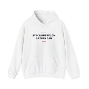 Op de afbeelding: Een witte hoodie met een kangoeroezak aan de voorzijde en lange mouwen. Op de borst staat de zwarte tekst "STACK OVERFLOW DRIVEN DEV" in een vet, schreefloos lettertype, geplaatst boven een dunne horizontale rode lijn.