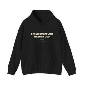 Op de afbeelding: Een zwarte hoodie met de tekst "METHODOLOGY" in kleine letters, gevolgd door "STACK OVERFLOW DRIVEN DEV" in een groter beige lettertype, een horizontale blauwgroene lijn en de kleine tekst "copy paste dev" gecentreerd op de borst.