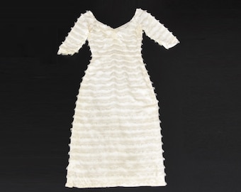 May include: A white, off-the-shoulder dress with a ruffled texture. The dress has short sleeves and a flowing skirt.