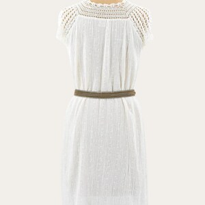 May include: A white, short-sleeved dress with a crochet neckline and a textured fabric. A brown belt cinches the waist. The dress is displayed on a mannequin.