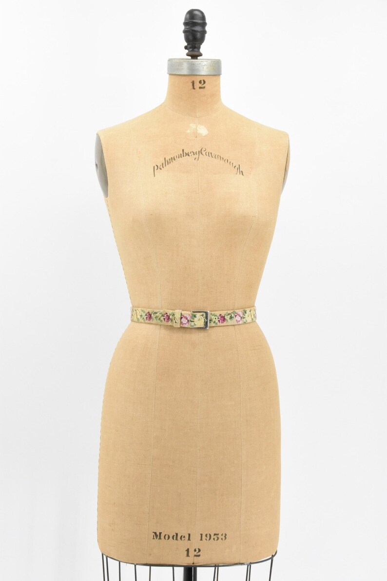 May include: A vintage floral patterned belt with a silver buckle on a dress form. The dress form is labeled "Palmenberg Cavanagh" and "Model 1953 12".