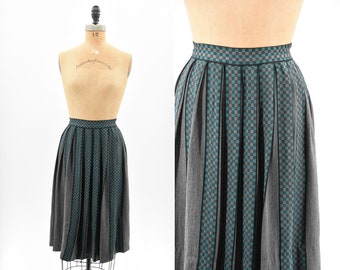 May include: A gray and teal plaid skirt with pleats. The skirt has a black waistband and is knee-length.
