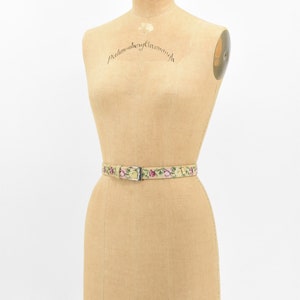 May include: A vintage dress form with a floral patterned belt. The dress form is made of tan fabric and has a label that reads "Pellham & Kay, Norwich".