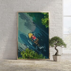 May include: A framed vertical wall art print featuring an overhead illustration of a small yellow boat floating on deep blue water. A figure in a red shirt and yellow hat sits inside the boat, surrounded by green foliage at the top and bottom edges.