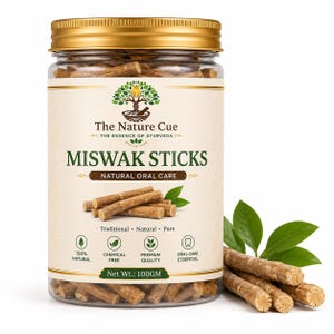 Peut inclure: Un pot en plastique transparent avec un couvercle doré contenant des bâtons de Miswak. L'étiquette indique The Nature Cue, Miswak Sticks, Natural Oral Care et Net Wt.: 100GM. Des bâtons en bois et des feuilles vertes sont devant le pot.
