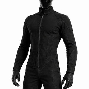 Puede incluir: Un mono negro de cuerpo entero con cierre de cremallera frontal, mangas largas y piernas ajustadas. La prenda se combina con un casco negro liso con finas aberturas oculares blancas, guantes negros y botas de cuero negro para un aspecto uniforme.