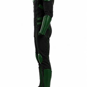 Puede incluir: Un disfraz de cuerpo completo en negro y verde con cuello alto, hombreras, protectores de antebrazo, rodilleras y espinilleras. El pecho muestra un emblema circular verde con un s&iacute;mbolo de linterna blanco. Vista de perfil.