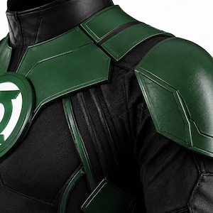 Puede incluir: Una parte superior de disfraz negra y verde con cuello alto, hombreras estructuradas y un emblema circular en el pecho con el logotipo blanco de Green Lantern. La prenda est&aacute; confeccionada con tela negra texturizada y paneles verdes lisos.