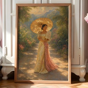 Op de afbeelding: Een ingelijste kunstdruk met een persoon in een lange, crèmekleurige japon met een roze sjerp, die een grote, goudgele parasol vasthoudt. De scène speelt zich af op een zonnig tuinpad omringd door weelderig groen en kleurrijke bloemen.