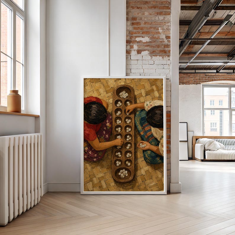 May include: A framed wall art print depicting two individuals sitting on a woven mat, engaged in a game of mancala. The wooden board features two rows of circular indentations filled with small white cowrie shells, captured from a top-down view.
