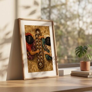 May include: A framed wall art print depicting an overhead view of two individuals playing a traditional wooden mancala board game with small white stones. The board is elongated with two rows of circular pits, and the players are wearing patterned clothing.