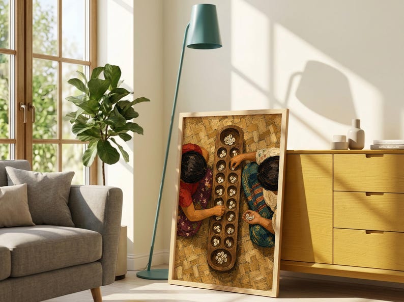 May include: A rectangular framed wall art piece featuring a top-down view of two individuals playing a traditional wooden mancala board game with small white shells on a woven mat surface, displayed in a light-colored wooden frame.