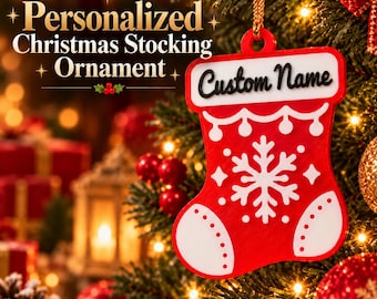 May include: A red and white Christmas stocking ornament featuring a white snowflake design, a white toe and heel section with dotted details, and a white top banner with the black text Custom Name, suspended by a gold cord.