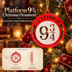 Może przedstawiać: Okrągła czerwono-biała ozdoba świąteczna z napisem Platform 9 3/4. Ozdoba ma 100 mm wysokości, 90 mm szerokości i 5,5 mm grubości, co zostało przedstawione na dołączonym schemacie wymiarów.