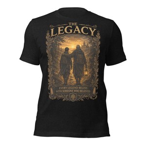 May include: A black short-sleeved t-shirt featuring a graphic print of two figures walking toward a distant castle at sunset. The text reads THE LEGACY and EVERY LEGEND BEGINS WITH SOMEONE WHO BELIEVED, framed by an ornate, leafy border design.