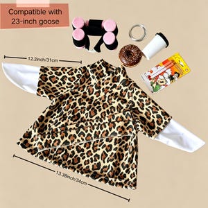 May include: A leopard print shirt with white sleeves, compatible with a 23-inch goose. Accessories include a black and pink dumbbell set, a chocolate frosted donut, a white cup, and a package of two pens. Dimensions are 12.2 inches and 13.38 inches.
