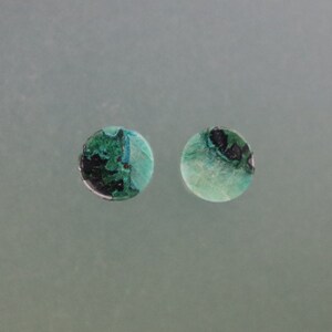 Può includere: Due cabochon rotondi decorativi, verdi e neri, su sfondo bianco.