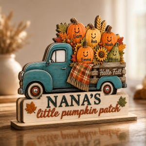 May include: A teal wooden truck decoration carrying pumpkins with the names Liam, Ava, Noah, Emma, and Mason. The truck bed features a plaid blanket and the text Hello Fall. The base displays the text NANA'S little pumpkin patch with leaf icons.