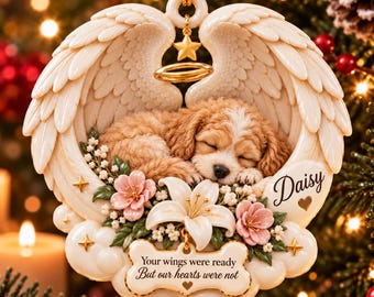 May include: A cream-colored hanging ornament featuring a sleeping puppy nestled within angel wings. It includes a gold halo, pink flowers, and a bone-shaped plaque with the text "Your wings were ready But our hearts were not" and "Daisy".