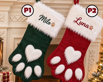 May include: Two paw-shaped Christmas stockings with white faux fur cuffs. The left stocking is dark green with the name Milo and a paw print embroidered in dark green. The right stocking is red with the name Luna and a paw print in red.