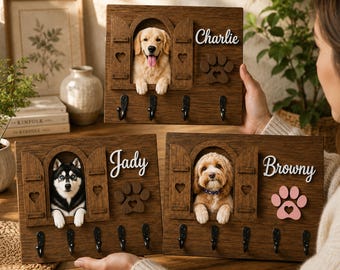 May include: Three rectangular wooden wall-mounted key holders featuring arched window cutouts with dog portraits, heart-shaped accents, and black metal hooks. Each board displays a custom name in white script and a decorative paw print cutout.