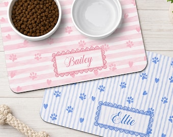 Puede incluir: Dos alfombrillas rectangulares para mascotas con esquinas redondeadas, una de rayas rosas y blancas con el nombre Bailey, y otra de rayas azules y blancas con el nombre Ellie. Ambas tienen huellas, corazones y un borde de encaje.